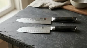 A Japanese chef's knife displayed alongside a European style knife to illustrate blade profile differences.